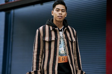 A young man posing in a jacket with brown and black stripes 