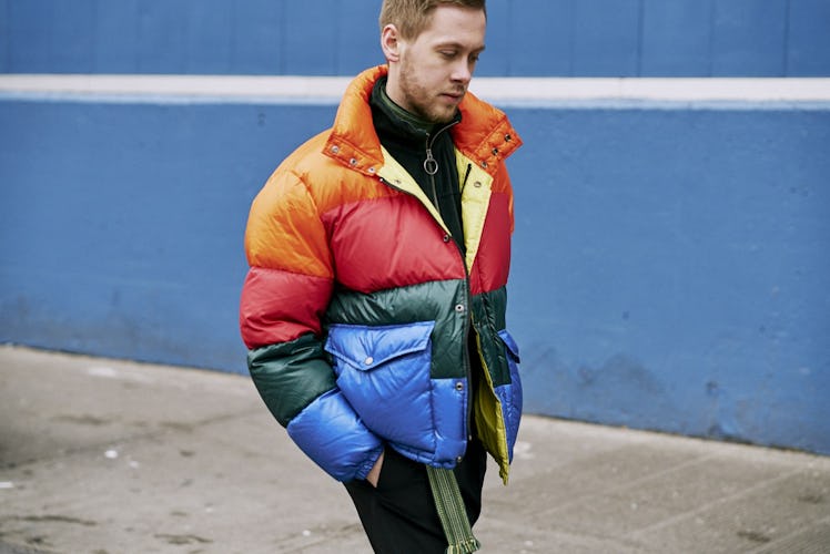 A man walking in a red, green, blue, and orange winter jacket 