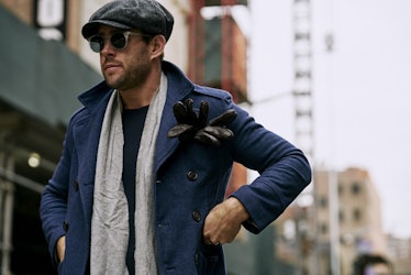 A man walking in a dark blue coat and cap