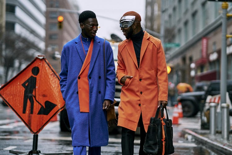 Two men in blue and orange coats walking down a street