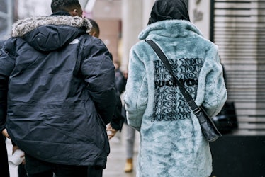 A man in a black jacket and a woman in a light blue jacket walking down a street 