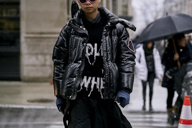 A man standing on a street while wearing a black shirt and a black jacket