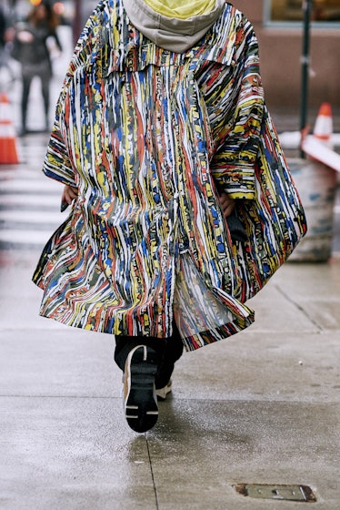 A model walking in a colorful coat down a street 