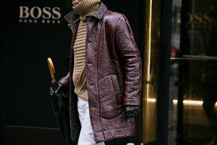 A man walking in a burgundy coat down a street 
