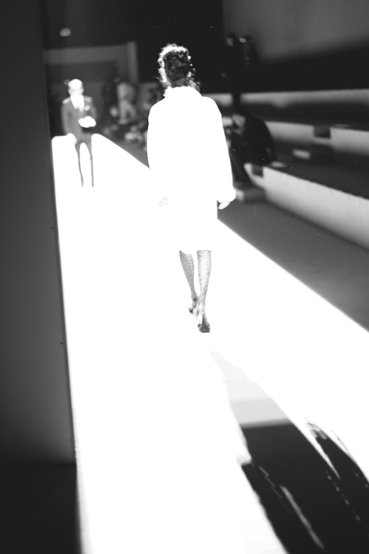 A woman walking down a runway in a white dress at the Tom Ford Fall 2018 show