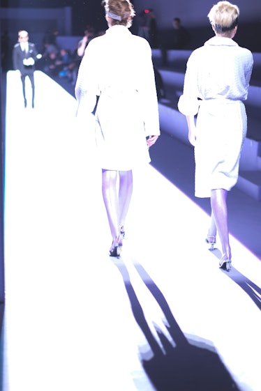 Two models walking in white dresses down a runway