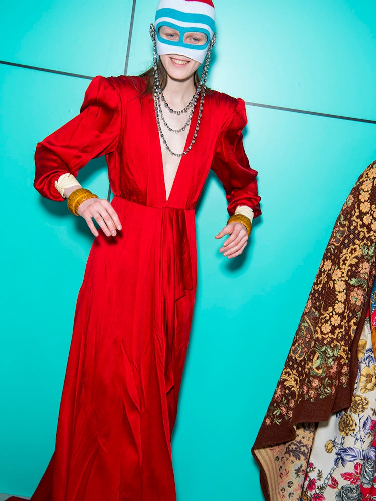 A model wearing a long red satin dress and mask over her face at the Gucci Fall 2018 runway show 