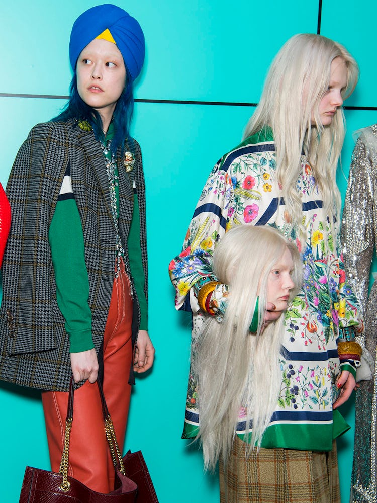 Backstage at the Gucci Fall 2018 runway show where one of the models is carrying a life-like replica...