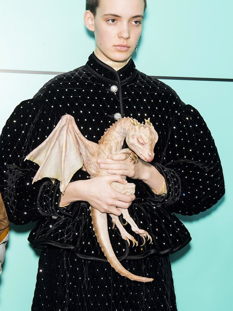 A model holding a life-like baby dragon at the Gucci Fall 2018 runway show 
