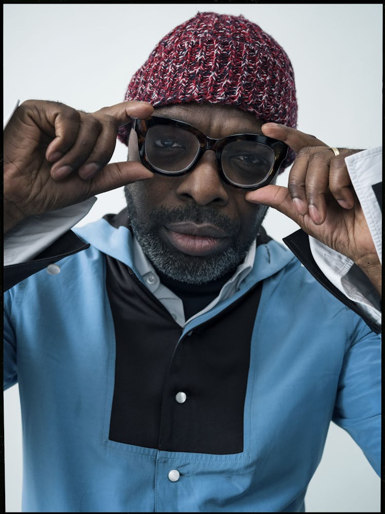 Duro Olowu in a black-blue Wales Bonner shirt, a red knit beanie and black glasses