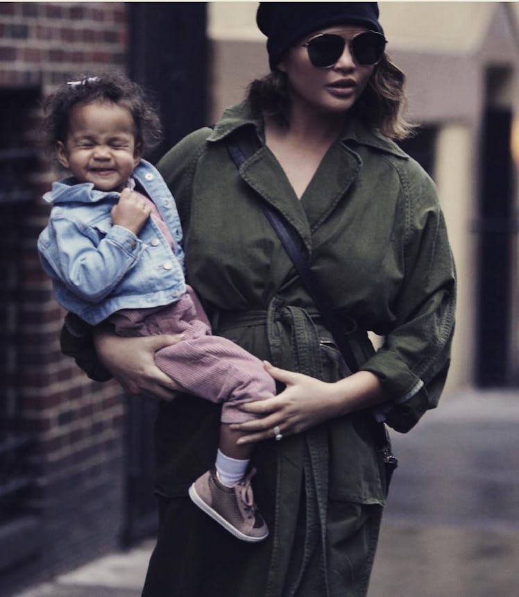 Chrissy Teigen, mom supermodel, walking and holding her daughter.