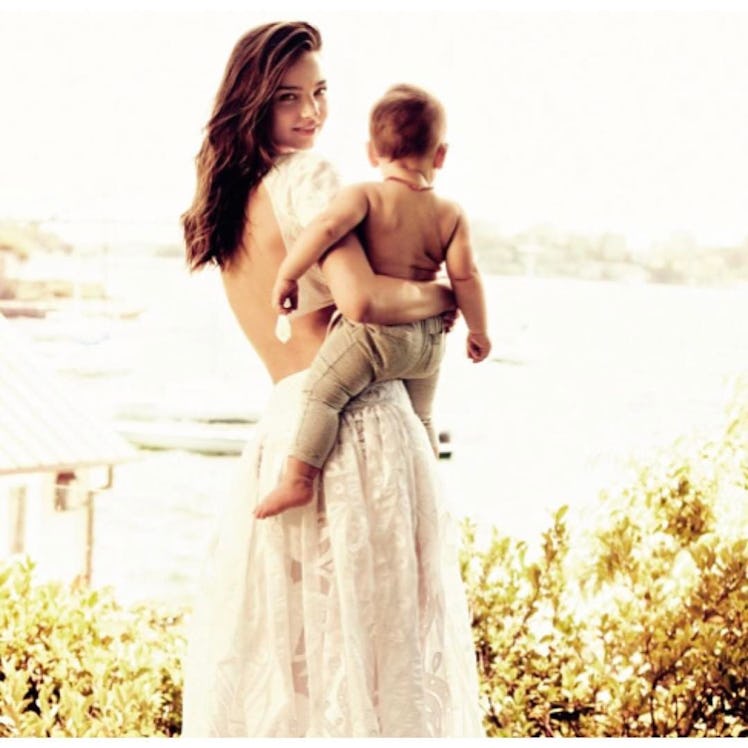 Mom and supermodel Miranda Kerr holding her son in maxi white lace dress.