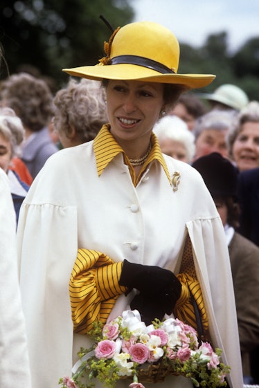 Princess Anne wearing a yellow hat and carrying flowers