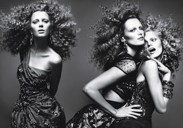 Three models with curly hair, wearing party dresses while posing for a photo