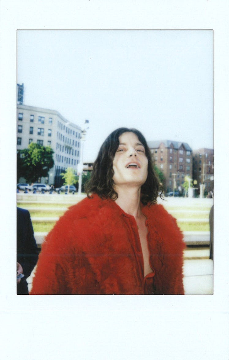 BØRNS in a red feather jacket looking up