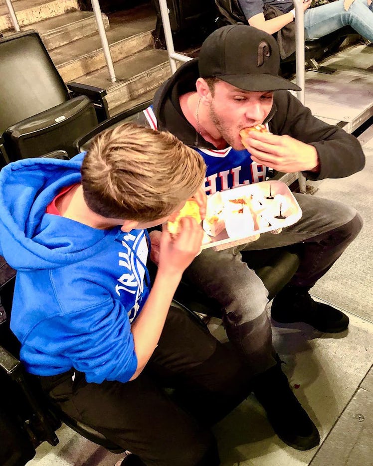 An Instagram post with Ryan Philippe and his son sitting in a stadium and eating fast food