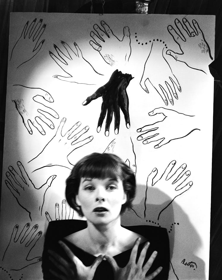 Audrey Hepburn, photographed by Cecil Beaton in front of a drawing of multiple hands