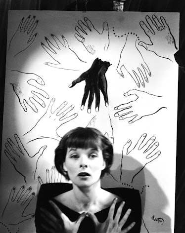 Audrey Hepburn, photographed by Cecil Beaton in front of a drawing of multiple hands