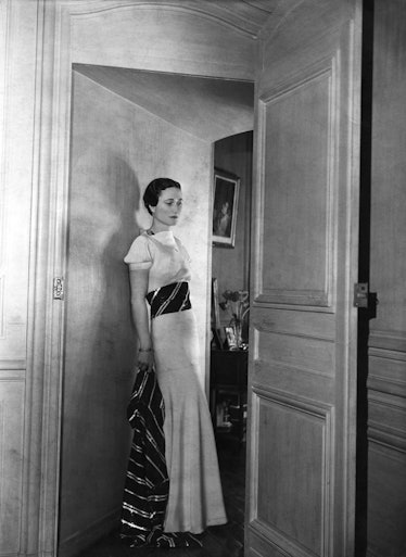 Wallis Simpson standing at a doorstep in a white dress photographed by Cecil Beaton