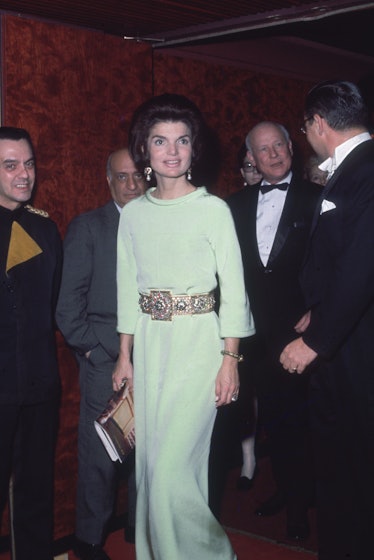 Jackie Kennedy in a floor-length pale green dress with an ornate chunky belt at the Metropolitan Ope...