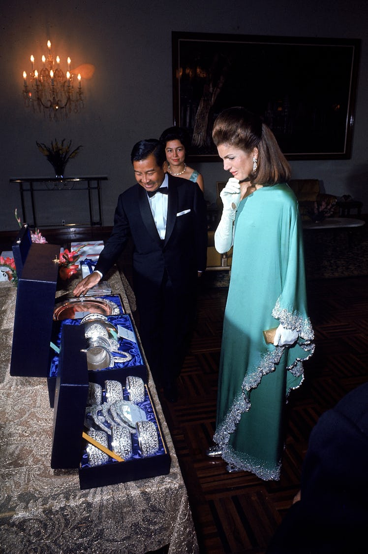 Jackie O in a teal one-shoulder dress meeting the Cambodian royals. 