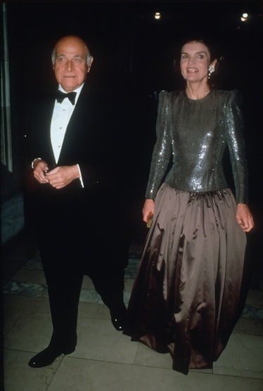 Jackie O at a gala at the New York Public Library in a floor-length dress, silver and shiny on the t...