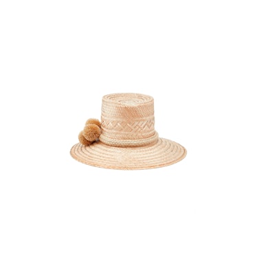 A straw hat with three beige pompoms by Johanna Ortiz