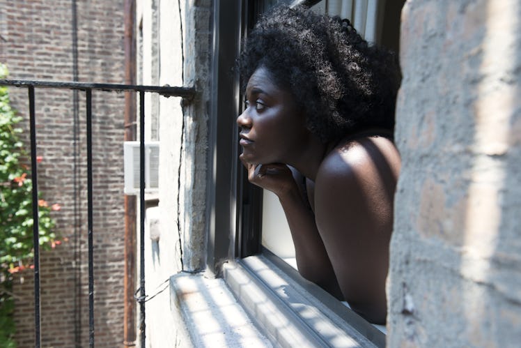 Danielle Brooks standing at her window and looking at the street 