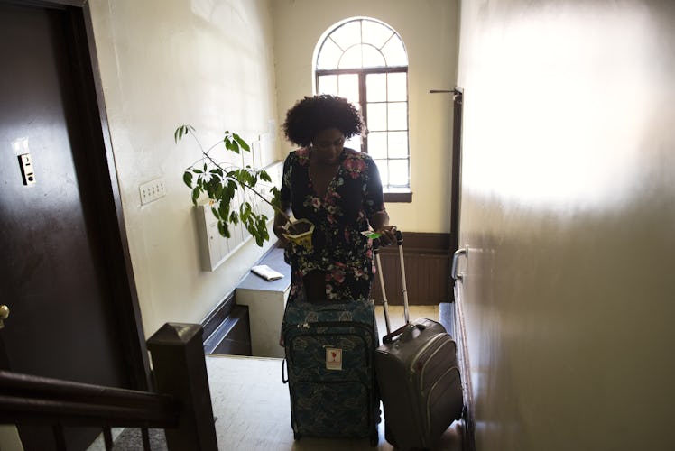 Danielle Brooks entering a flat with two suitcases