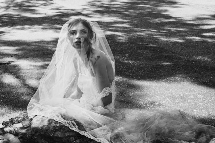 Imogen Poots sitting on ground while wearing a white dress 