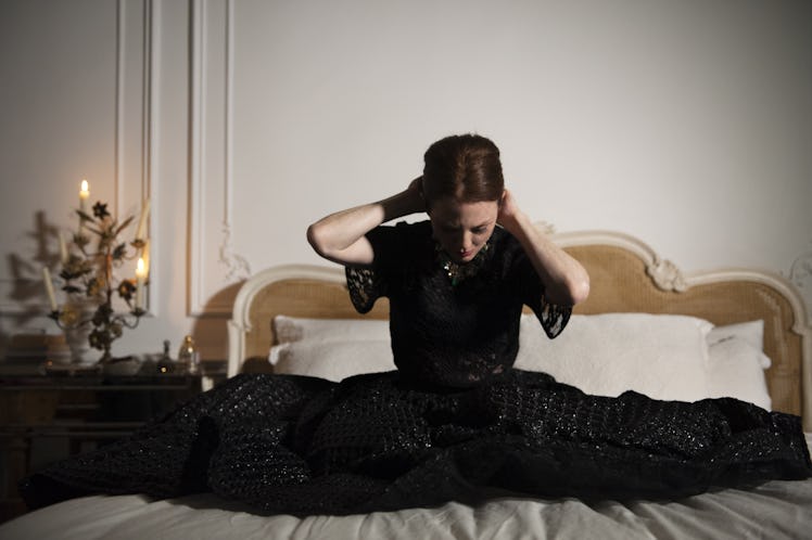 Julianne Moore sitting on her bed while wearing a black dress 