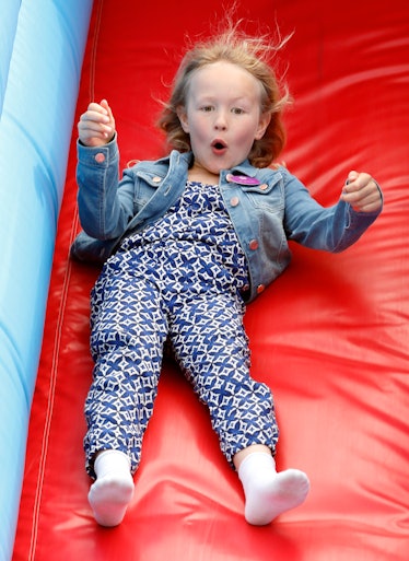 Savannah Phillips goes down the red slide with her hands in the air.