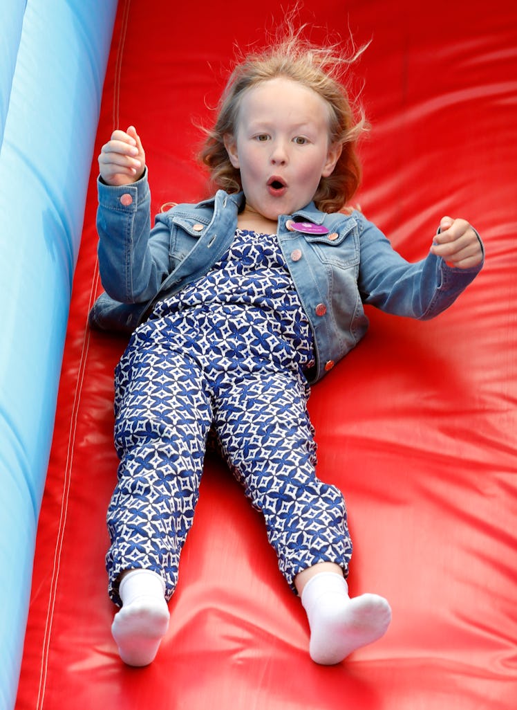 Savannah Phillips goes down the red slide with her hands in the air.