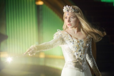 Michelle Williams as Glinda the Good Witch wearing a white dress and a crown, casting a spell