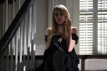 Emma Roberts sitting on a staircase, smoking, wearing a black dress portrayed as a Witch