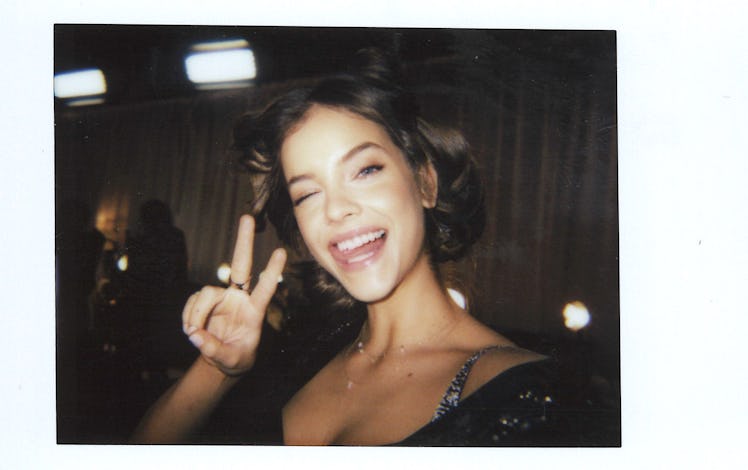 Barbara Palvin showing the peace sign with her hand and sticking her tongue out 