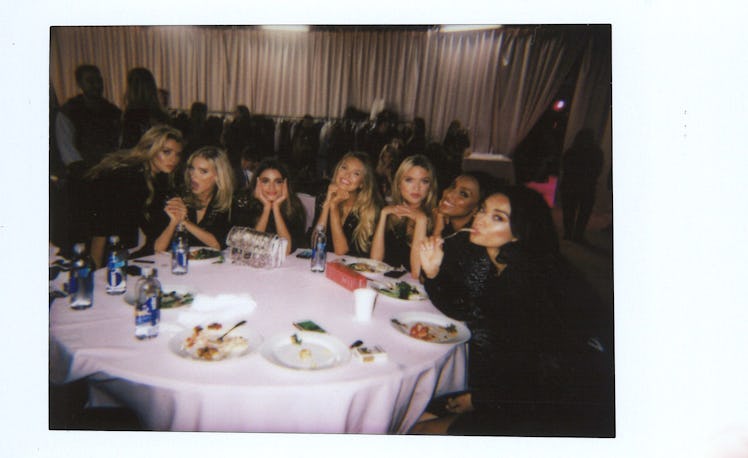 Victoria's Secret models sitting at a white round dining table having dinner 