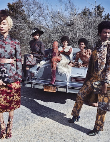 Five models posing in blazers and skirts next to an old timer car