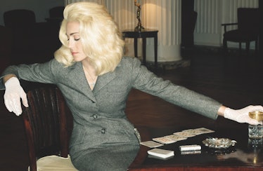 Madonna sitting while wearing a grey blazer 