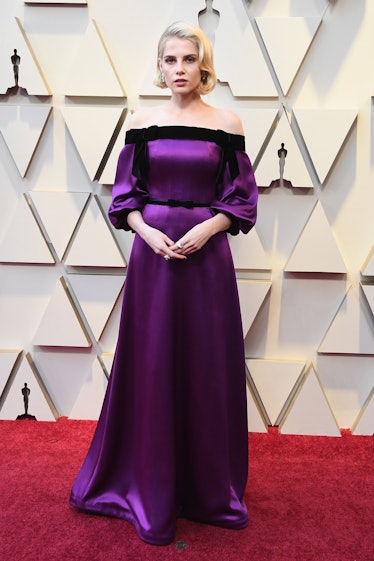 Lucy Boynton attending the 2019 Oscars Red carpet in a dark purple satin gown
