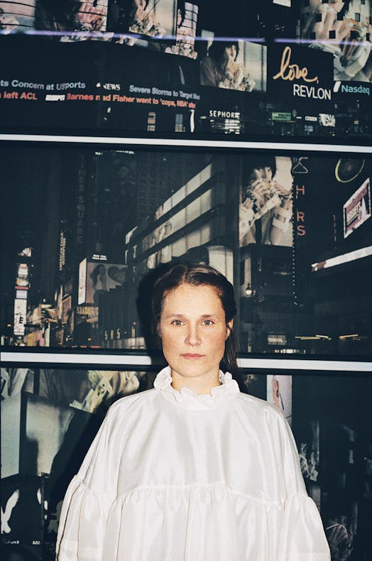 Cecilie Bahnsen in a white blouse with a night life city wallpaper behind her