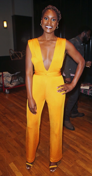 Issa wearing golden yellow jumpsuit with plunging neckline