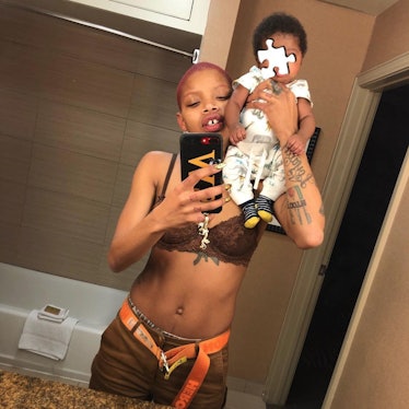 Mirror selfie of an iconic mom supermodel, Slick Woods, holding her son with his face hidden