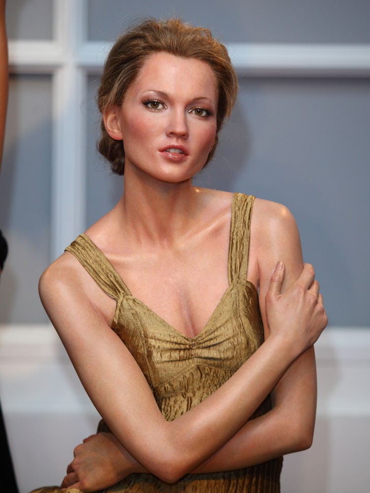 A Kate Moss wax figure in a gold dress at Madame Tussauds with crossed arms