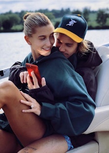 Hailer Bieber sitting in the lap of Justin Bieber on a boat 