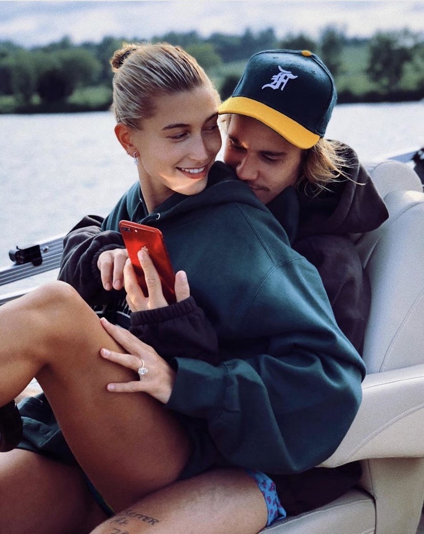 Hailer Bieber sitting in the lap of Justin Bieber on a boat