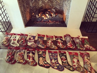 18 Christmas stockings placed in two rows next to a fire place