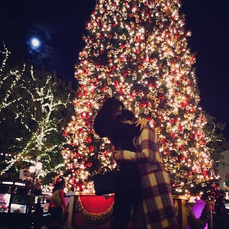 Kendall and Kylie Jenner hugging in front of a large Christmas tree