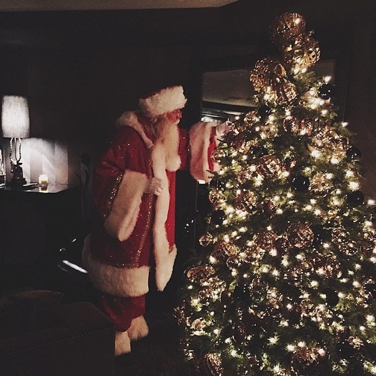 A man dressed as Santa Claus looking at a Christmas tree at a Kardashian Christmas party