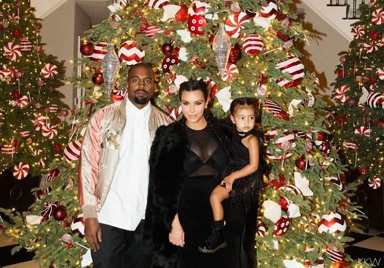 Kanye West, Kim Kardashian, and North West posing next to a Christmas tree